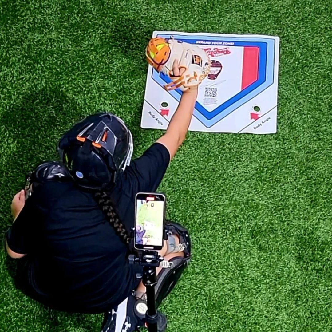 Person in a catcher's uniform preparing to catch a baseball on a green field